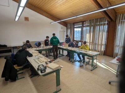 Schüler sitzen an Tischen und bauen einen iPad‑Halter aus Holz