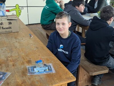 Ein Schüler sitzt an einem Tisch mit elektronischen Bauteilen vor sich