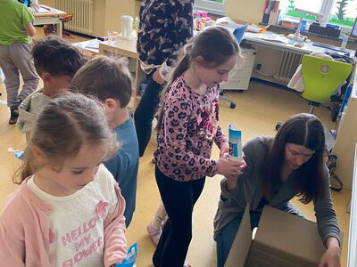 Kinder nehmen sich einen Zahnputzbecher aus einem Karton