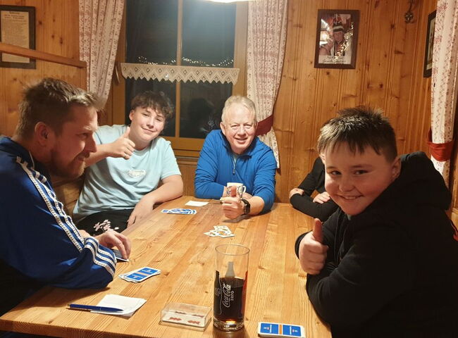 Schüler und Lehrer beim Karten spielen in einer Hütte