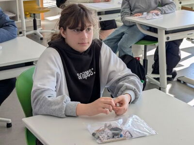 Schüler sitzen an Bänken und haben Tüten mit Elektronik vor sich