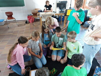 Schüler sitzen im Kreis am Boden und lesen aus einem gelben Brief