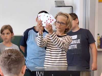 Ein Schulkind hält gefächerte Spielkarten hoch