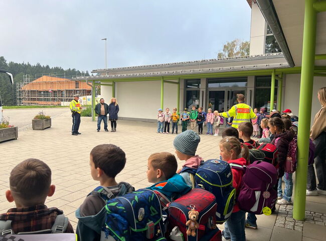 Schulkinder und Polizei stehen vor dem Schulgebäude