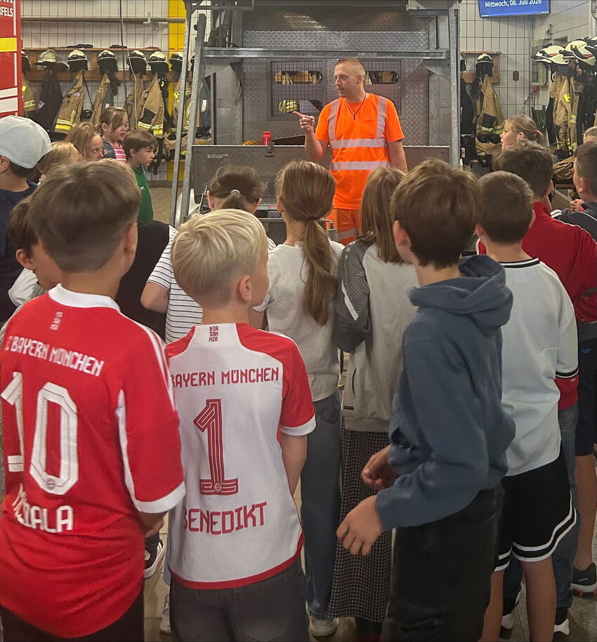 Ein Feuerwehrmann spricht mit Kindern im Gerätehaus